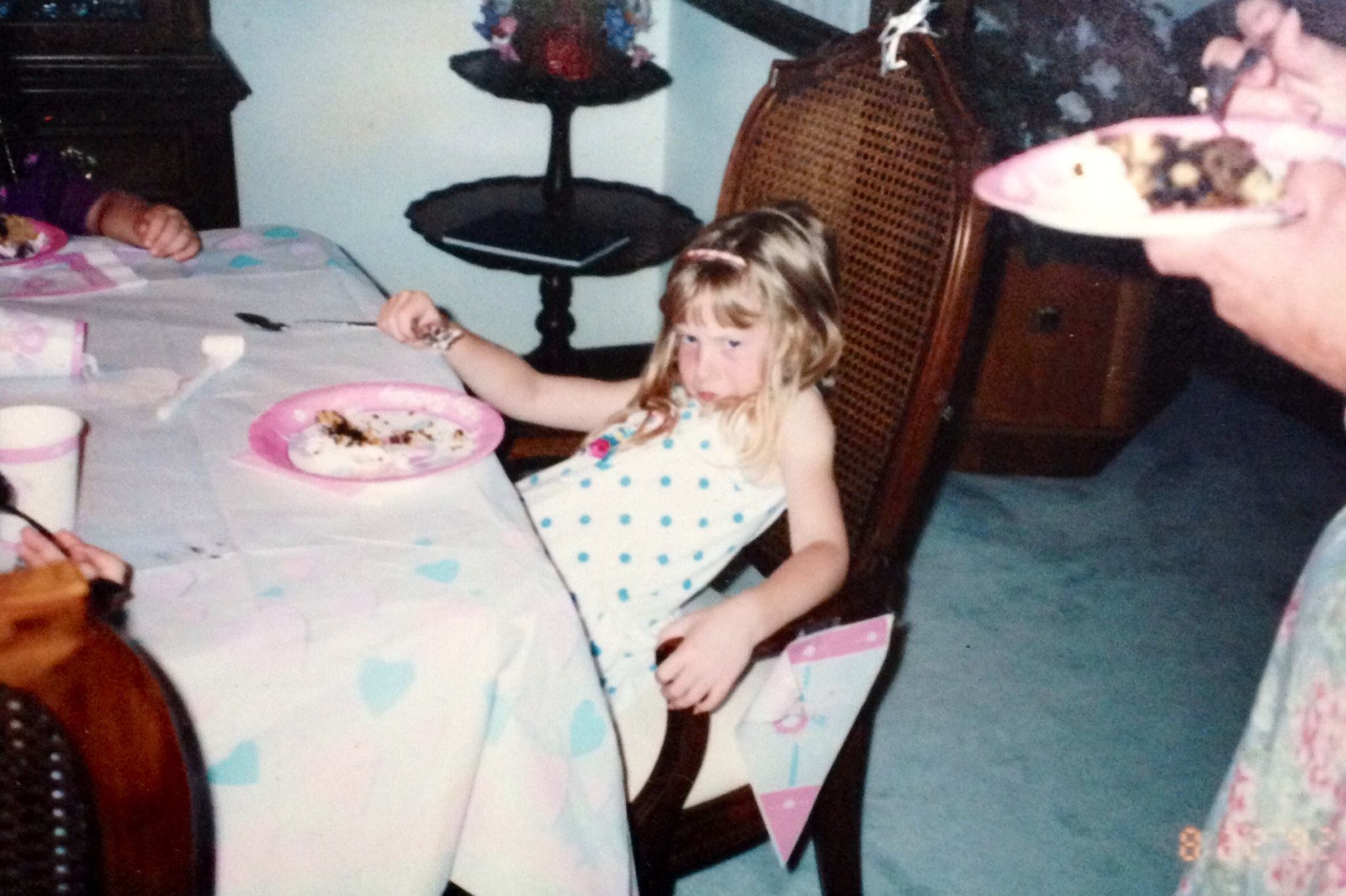 Amelia as a child, pouting at a birthday table